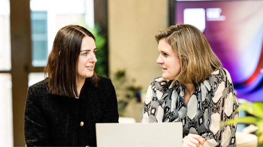 Two business women having a discussion infront of a laptop computer