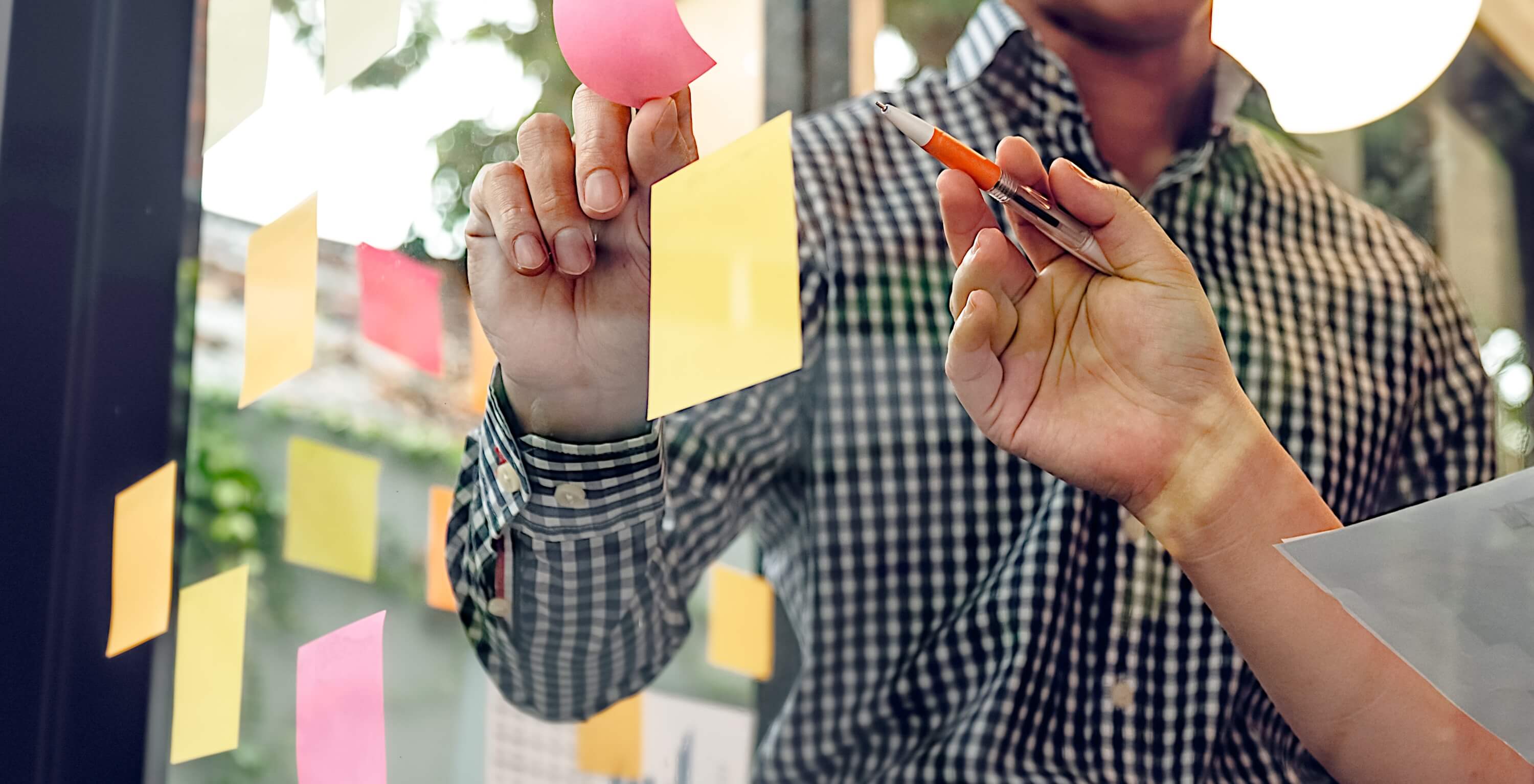 A man and woman discussing engagement whilst placing sticky-notes on a glass wall