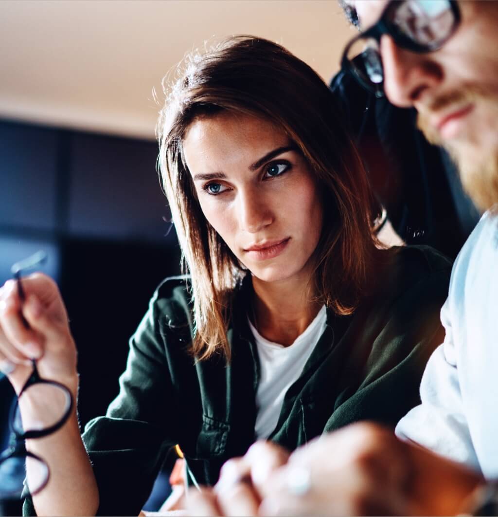 A woman looking purposefully at her colleague's laptop