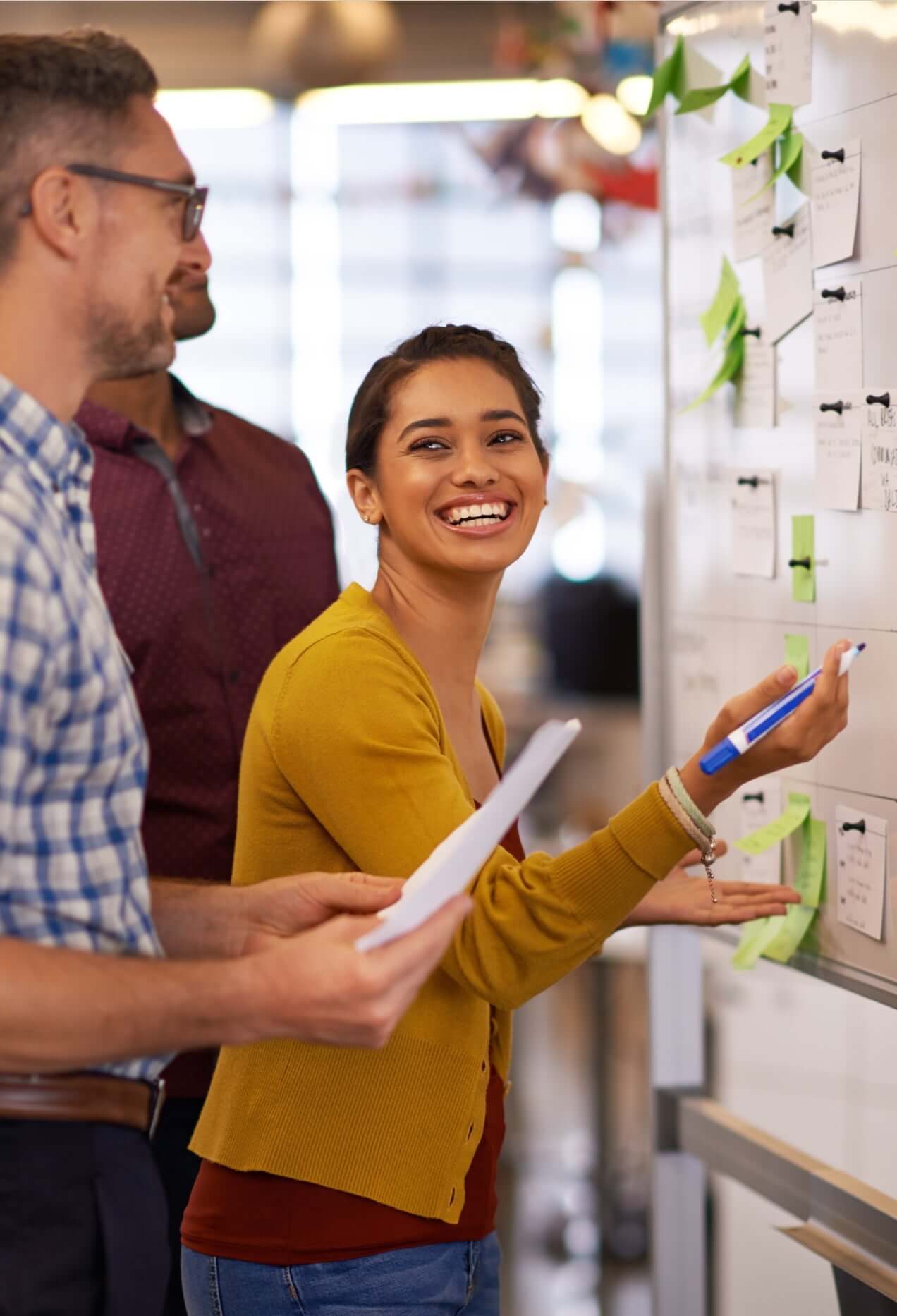 A young woman smiling at her colleague as she writes on a whiteboard