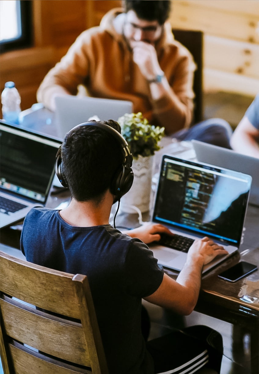 A developer sat at a table, writing code with his colleagues