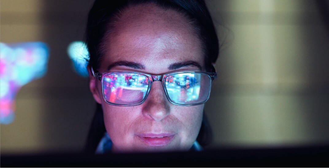 A female engineer examining AI technology with her screen reflected in her glasses