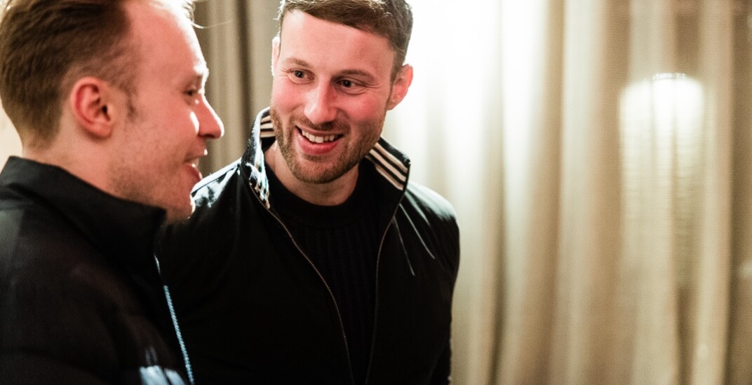 Two men smiling as they talk to one another