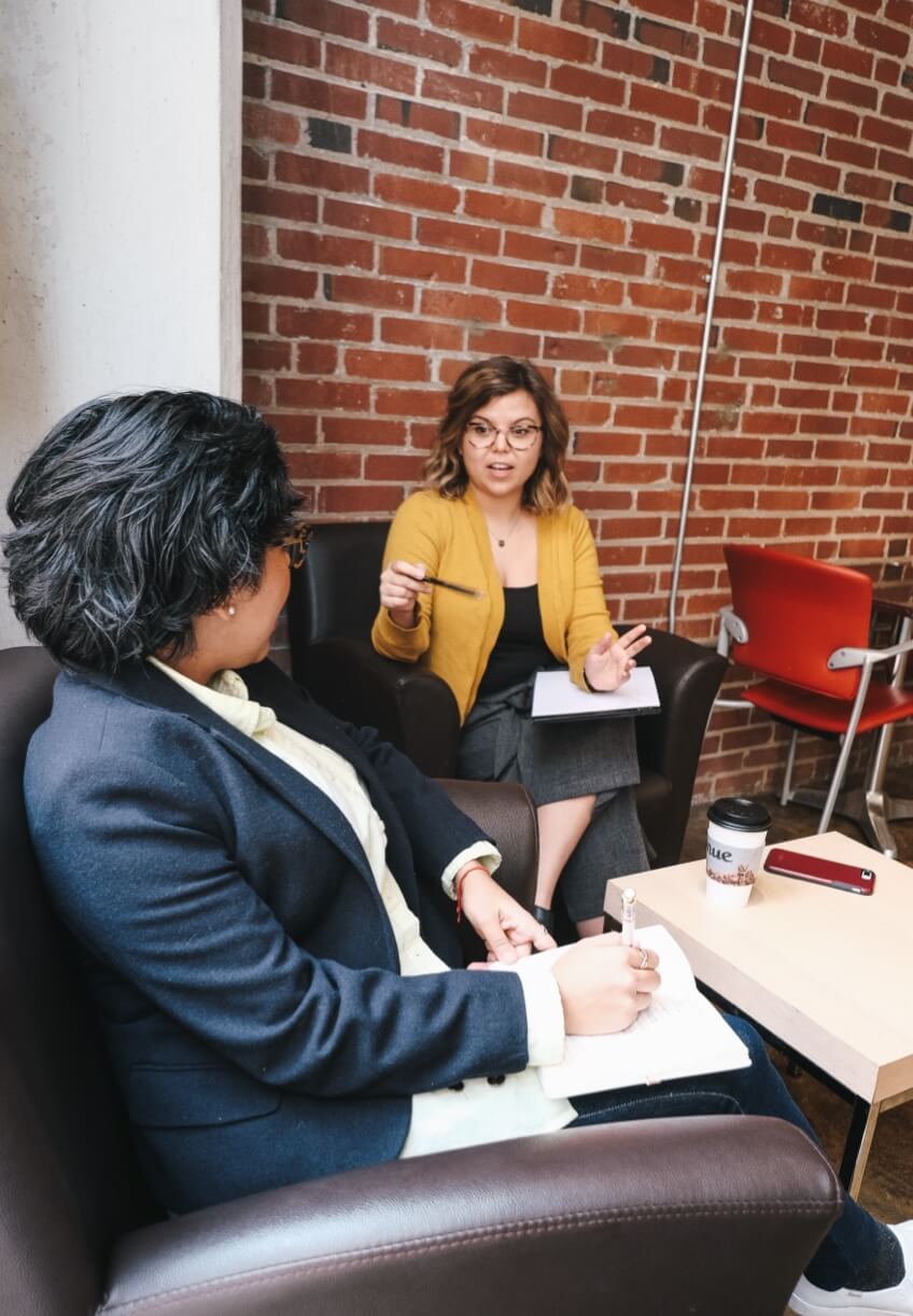 A woman taking notes as another woman talks to her