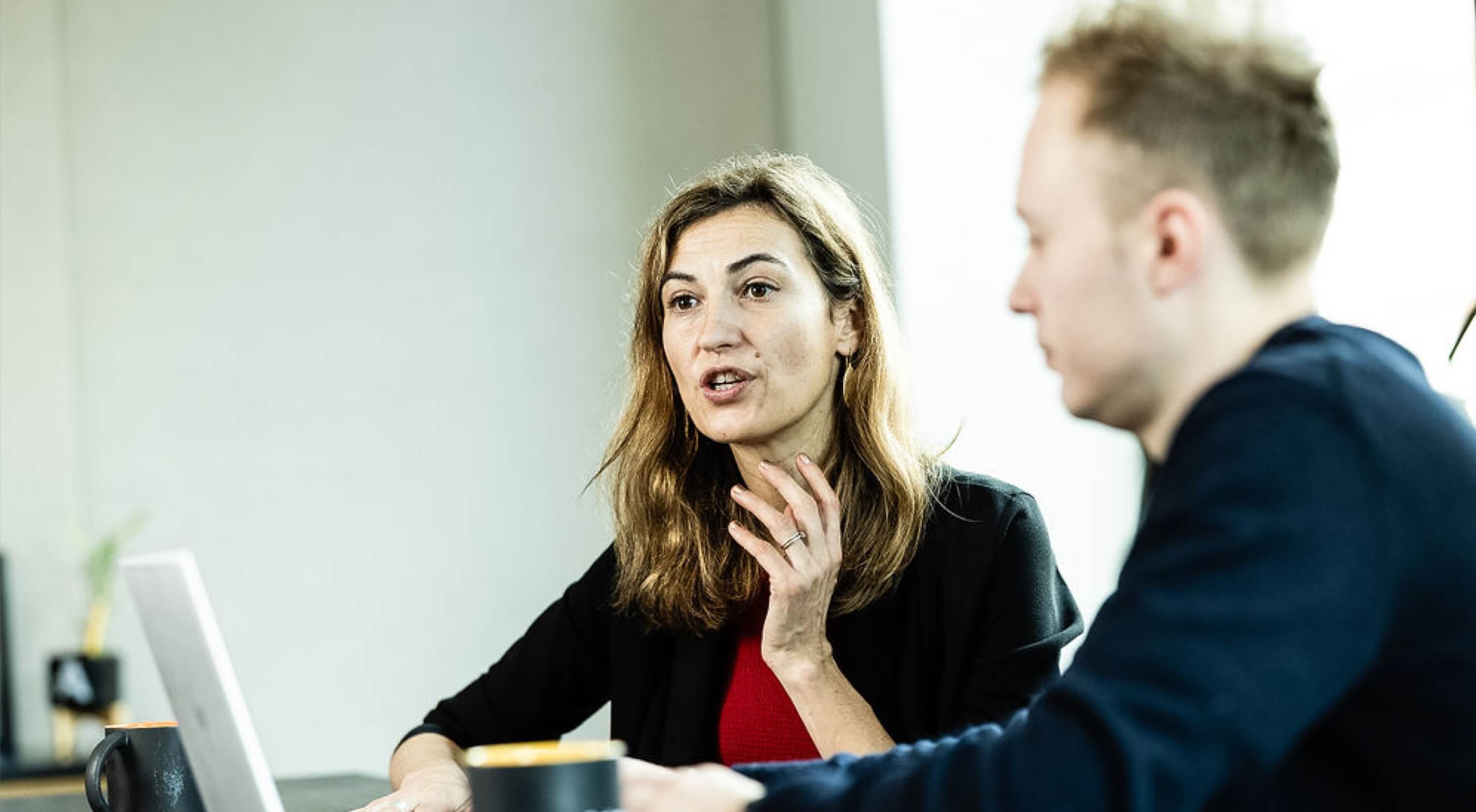 A man and woman discussing the contents of a laptop computer screen