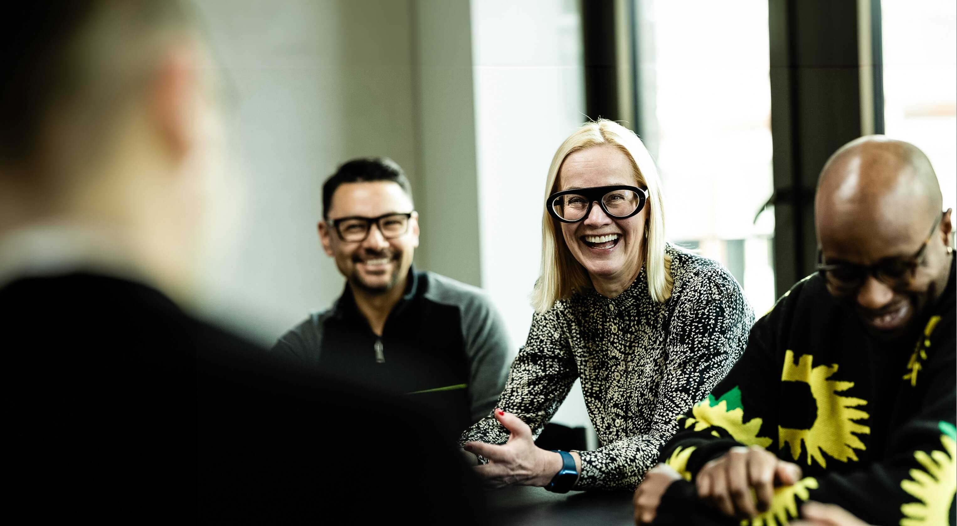 A woman and two met sat happily at a meeting room table