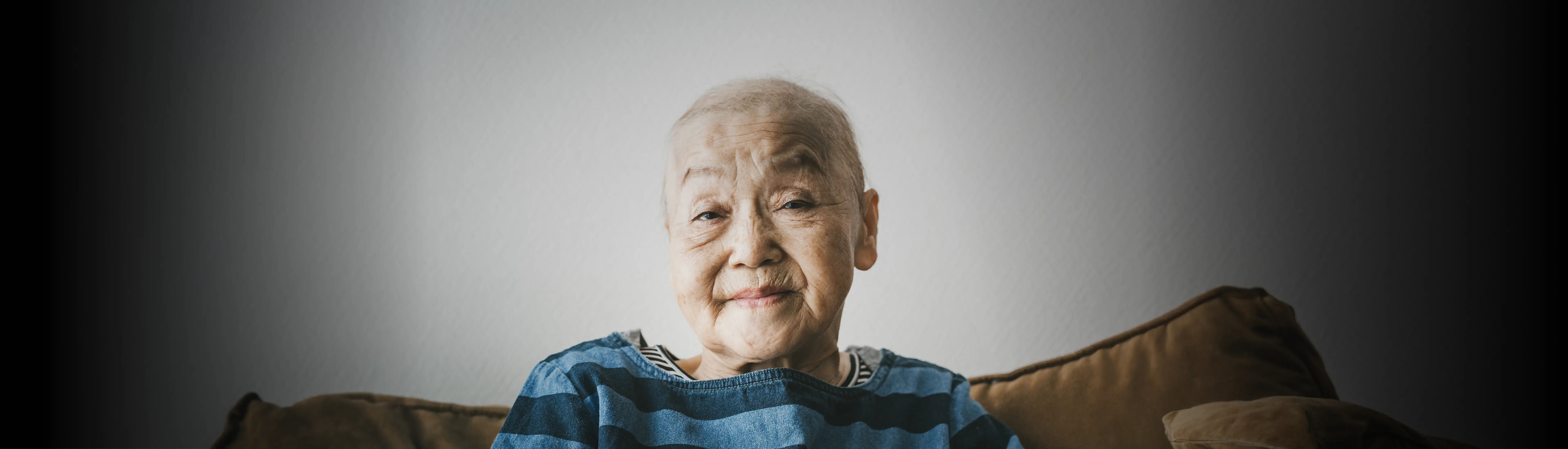 Image showing older woman in blue sweater looking straight at camera, surrounded by Avalere Health A-frame.